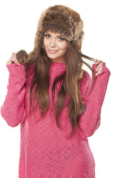 pretty and nice girl in a pink sweater and a fur hat posing on a