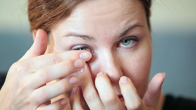 Woman inserting clear transparent contact lens in her eye