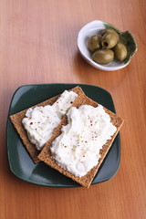 Snack of rye crisps witn spicy cream cheese and olives