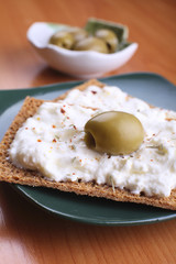 Snack of rye crisps witn spicy cream cheese and olives