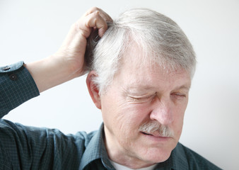 senior man scratches his itchy scalp