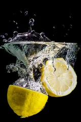 Papier Peint photo Lavable Éclaboussures deau deux moitiés de citron tombent dans l& 39 eau sur un fond noir