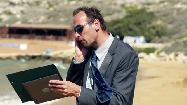 Businessman screeming to the cellphone on the beach, slow motion