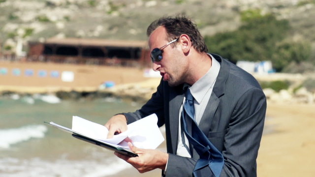 Businessman screeming to the cellphone on the beach, slow motion