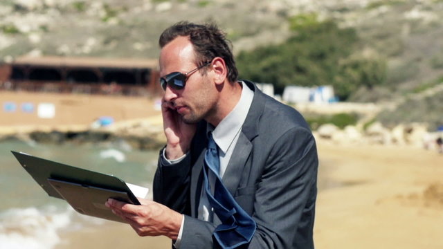 Businessman screeming to the cellphone on the beach, slow motion