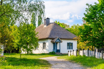 Fototapeta na wymiar A typical antique Ukrainian country house with a thatch roof, in the countryside near Kiev 