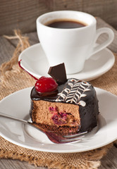 Sweet dessert fruitcake with a cherry and a cup of coffee