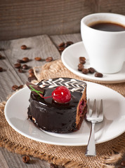 Sweet dessert fruitcake with a cherry and a cup of coffee