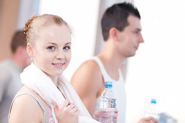 Man and woman drinking water after sports in gym