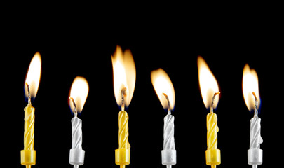 Golden and silver burning candles on black background