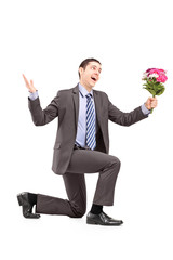Young man kneeling and holding a bunch of flowers