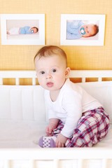 Fototapeta premium Five-months baby sits in white bed