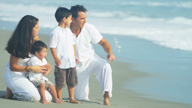 Hispanic family on Summer holiday playing on sandy beach