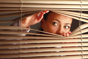 Portrait of a woman looking through out the blinds