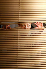 Portrait of a woman looking through out the blinds