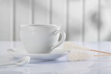 Obraz na płótnie Canvas a coffee cup with spoon and sugar stick on white table