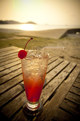 red spirit drink in tall glass decorated cherry by the sea