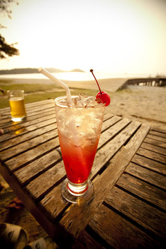 Red Cocktail Drink In Tall Glass Decorated Cherry By The Sea