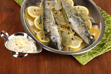 Fish in frying pan with spices and lemon
