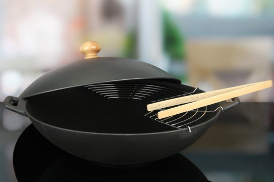 Black wok pan on kitchen oven, close up
