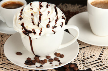 Cup of whipped cream coffee on wooden table close up