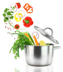 Fresh vegetables falling into a stainless steel casserole pot