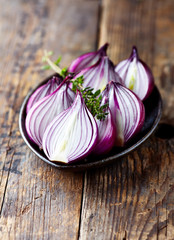 Halved red onions and thyme on a plate
