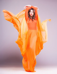 beautiful woman in long orange dress posing dynamic - 50081227