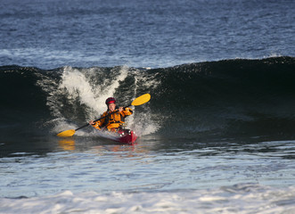 Kayak surfer escaping from big wave on rough sea