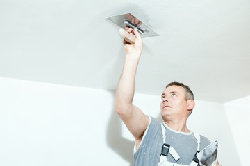 Plasterer spreading out plaster with trowel over the ceiling
