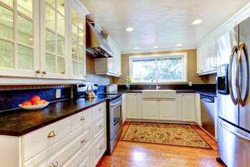 White kitchen interior with large sink and window.