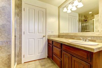 Bathroom with stone tiles and shower with wood cabinets.