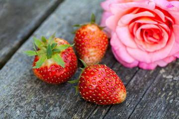 strawberries and pink rose on wooden table