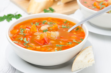Vegetable soup with white beans in a bowl and spoon horizontal