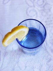 Glass of water with lemon on white cloth