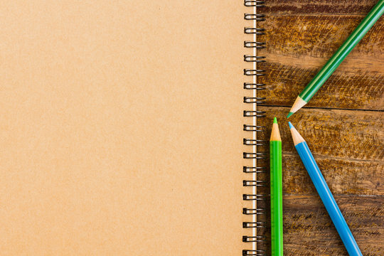 Gray notebook with colorful pencils on the wooden table