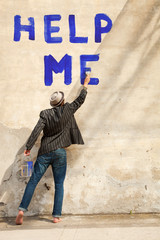 man writes on a wall help me