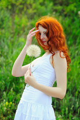 Obraz premium Young redhead female with big dandelion.