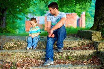 father and son talk, while sitting on old stairs outdoor