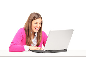 Smiling young female sitting and looking at a laptop