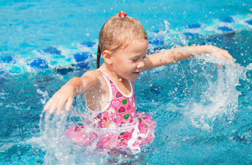 Fototapeta na wymiar happy little girl splashing around in the pool