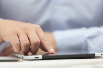 Hands of the man in the blue shirt are holding a tablet computer