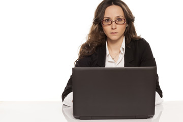 serious girl with glasses working on laptop on white background