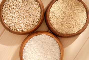 Some oatmeal, millet, rice are in woody bowls.
