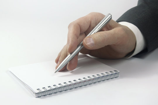 business person hand with pen over notebook
