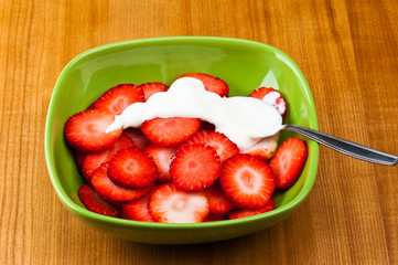 strawberry with cream on a plate with a spoon