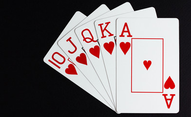 Royal flush of hearts over black background