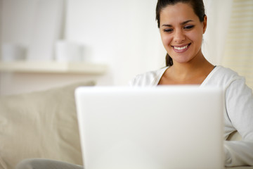 Young woman sitting on couch and working on laptop