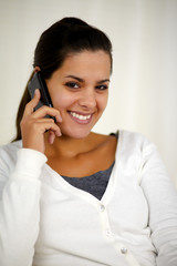 Young woman speaking on cellphone looking at you