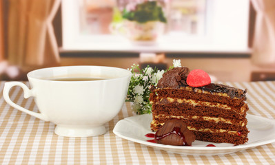 Cup of tea and delicious cake on window background
